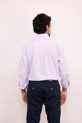 Camisa de corte clásico confeccionada en algodón, con diseño de rayas verticales finas en color rosa sobre fondo blanco. Presenta cuello abotonado, cierre frontal con botones, mangas largas con puños abotonados y un bolsillo en el pecho con el logo de la marca bordado.