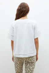 Remera blanca de algodón con mangas cortas y detalle de vainillas en los bordes.