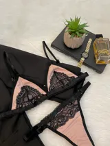 Conjunto de lencería compuesto por un corpiño triangular y una tanga, confeccionados en lycra color beige con detalles de encaje negro y elásticos a tono.