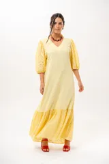 Vestido largo amarillo mantequilla con escote en V, mangas abullonadas y volados en el bajo con detalles de broderie.