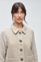 Campera corta con cuerpo de lana tejida en textura tweed y mangas de punto liso en color marrón. Presenta cuello camisero, cierre frontal con botones y bolsillos frontales tipo plaque.