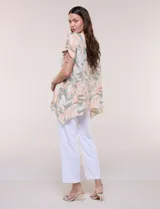Blusa de silueta holgada confeccionada en crepé liviano, con estampado abstracto en tonos rosados, verdes y blancos. Presenta escote redondo amplio, hombros caídos con hilera de botones decorativos, mangas cortas con dobladillo y ruedo asimétrico en picos.