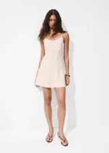 Vestido corto de color beige con diseño fluido, tejido plisado, cuello redondo y tirantes finos ajustables.