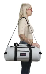 Bolso JanSport Superbreak Away Duffel, color blanco con detalles en negro. Cuenta con asas de mano y correa ajustable para el hombro, bolsillo frontal con cierre y compartimento principal con cierre de cremallera.