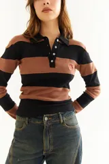 Top de manga larga con diseño de rayas horizontales en tonos negro y marrón, cuello polo con cierre de botones y bordado pequeño en el pecho.