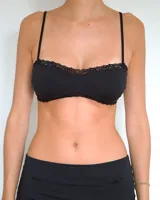 Bra estilo bandeau con breteles finos ajustables, confeccionado en tela lisa con delicados detalles de encaje en los bordes superior e inferior.