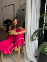 Mono largo de lino color amarillo, con escote en V, tirantes finos y detalles de costuras decorativas blancas en el escote y en los bajos de las piernas anchas.