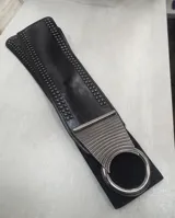 Cinto ancho tipo faja, color negro, confeccionado en material elástico con múltiples filas de tachas metálicas en los laterales.