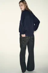 Blusa de manga larga en color azul marino, con cuello solapa y lazo frontal. Presenta detalles de pespuntes bordados en color crema a lo largo del cuello, lazo, cierre frontal y puños. Cierre frontal con botones.