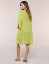 Vestido playero tipo túnica de corte holgado color rosado, confeccionado en tejido semi transparente con textura sutilmente arrugada. Cuenta con escote en V pronunciado, mangas estilo kimono de caída fluida y aberturas laterales en el ruedo irregular.