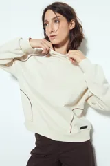 Canguro negro de silueta amplia con capucha integrada y detalles de líneas blancas que recorren el frente y las mangas.