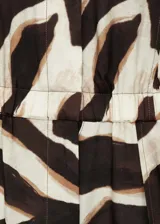 Mono largo de tejido fluido con estampado animal print. Presenta cuello camisero, cierre frontal de botones ocultos, diseño sin mangas y cintura con elástico. Incluye dos bolsillos de parche en la parte delantera.