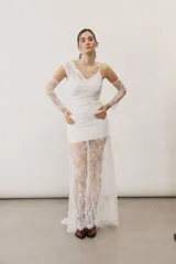 Vestido largo blanco de encaje con diseño asimétrico, tirante fino en un hombro y falda transparente.