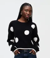 Suéter de punto negro con diseño de lunares blancos en jacquard, cuello redondo, mangas largas con sisa desplazada y detalles de rib en puños y dobladillo.