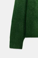 Sweater de punto color verde oscuro, con cuello redondo, manga larga y hombreras marcadas.