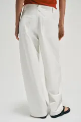 Pantalón barrel color azul marino, de tiro bajo, pernera holgada con diseño redondeado que se estrecha hacia el tobillo, con bolsillos delanteros y cierre frontal.
