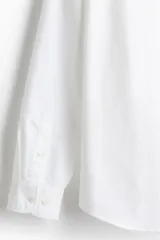 Camisa Oxford de algodón blanca, de corte regular fit, con cuello americano, bolsillo frontal aplicado y mangas largas con puños abotonados.