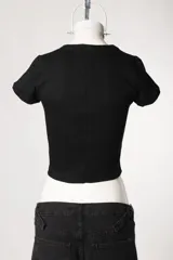 Remera de morley de manga corta, color gris, ajustada al cuerpo y elastizada, con bordado estilo college con la inscripción 'New York' en el pecho.