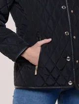 Campera matelaseada Michael Kors, de color beige con ribetes de ecocuero marrón. Cuenta con cuello con solapa, cierre frontal con broches metálicos, bolsillos laterales con cierre y mangas largas.