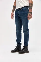 Jean de corte slim, entallado en cadera y muslos con ajuste gradual desde la rodilla hasta el tobillo. Presenta un lavado azul oscuro clásico con costuras reforzadas y cierre frontal con botón y cremallera.