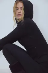 Campera deportiva de corte ajustado confeccionada en tejido funcional con tecnología SoftMove y DryMove. Presenta capucha, cierre frontal con protección para el mentón, bolsillos laterales con cierre y mangas extralargas con abertura para el pulgar.