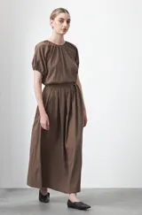 Top negro de manga corta con escote redondo y frunces en la costura de la sisa, creando un efecto de manga abullonada. El tejido parece ligero y con textura.