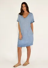 Vestido corto color celeste con textura de lino, escote en V y mangas cortas con terminación desflecada. Tiene bolsillos laterales.