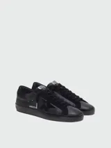 Zapatillas Golden Goose Super-Star de hombre, confeccionadas en napa y gamuza negra, con el diseño característico de la estrella en el lateral, suela de goma y acabado desgastado.