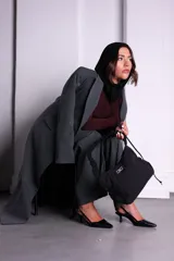 Bolso de nylon color naranja quemado, con textura sutil y manija fruncida. Presenta un parche rectangular negro con el logo 'KUL.' en blanco en el frente.