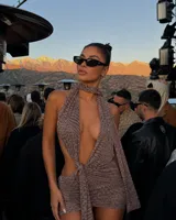 Vestido corto con estampado animal print, diseño halter con escote profundo y detalle de nudo frontal. Presenta una falda ajustada con frunces laterales.