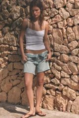 Top corsetero blanco de escote redondo con tirantes finos ajustables. Presenta detalles de frunces en el pecho y costuras verticales marcadas.