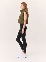 Chaleco puffer de corte cropped y diseño acolchado, con cuello alto y cierre frontal completo. Presenta un acabado liso en color marrón oscuro.