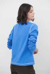 Remera de manga larga con cuello redondo, confeccionada en tejido de punto gris melange con costuras visibles en contraste.