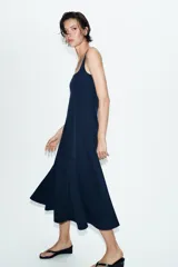 Vestido midi de color beige con escote cuadrado y tirantes anchos. Presenta un diseño entallado en el torso con costuras verticales marcadas y una falda con caída evasé.