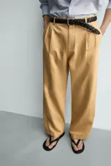 Pantalón chino straight fit de corte recto y holgado, color tostado, con pliegues frontales en la cintura, bolsillos laterales y cierre con cremallera y botón.
