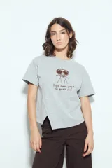 Remera gris de manga corta con estampa frontal de un personaje con gafas de sol y la frase "llegué tarde porque no quería venir". Tiene un corte relajado y aberturas laterales.