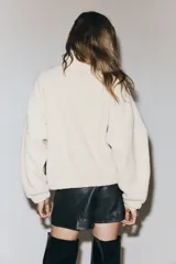 Campera de sherpa con cuello alto, hombros caídos, cierre frontal oculto con botones a presión y bolsillos laterales insertados. Diseño forrado con puños elásticos.