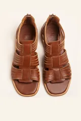 Sandalia de cuero color marrón chocolate, con suela plana y diseño calado con detalles trenzados.