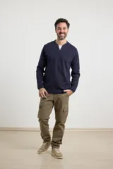 Remera de manga larga en tejido elastizado, color azul, con cuello tipo camisa, cartera con botones y detalles en eco gamuza en la base del cuello y la cartera.