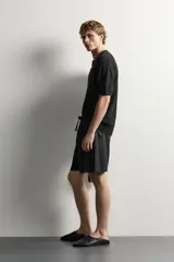 Bermuda de lino negro de corte relaxed fit, con cintura elástica ajustable mediante cordón y bolsillos frontales.