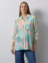 Camisa estampada con hojas en tonos celeste, naranja y verde. Tiene cuello con solapa, abertura central con botones, bolsillos aplicados en la parte delantera y mangas 3/4 con lazo.