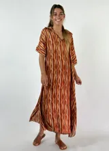 Vestido largo con cuello camisero y mangas cortas, con estampado de rayas verticales en tonos naranja, marrón y blanco.