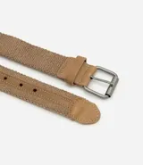 Cinturón trenzado elástico color marrón claro, con detalles en cuero sintético color camel en la presilla y la punta. Posee hebilla metálica de estilo rústico.