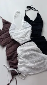 Conjunto de dos piezas color marrón, compuesto por un top estilo halter con detalles de encaje y una minifalda ajustada con frunces laterales.