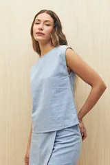 Top sin mangas de lino y viscosa, color negro, con escote redondo y caída relajada. Presenta hombros levemente marcados y botones forrados en la espalda.