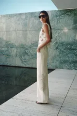 Jean de tiro alto y piernas amplias, color crudo, confeccionado en denim de algodón rígido, con detalles de bordado estilo crochet tono sobre tono en los laterales.