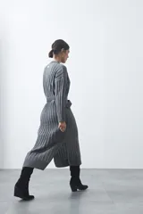 Vestido midi de punto en color gris, con diseño de tejido acanalado vertical, cuello redondo y mangas largas. Presenta una silueta recta y fluida.