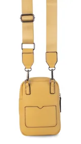 Bandolera pequeña de diseño compacto en color mostaza, confeccionada en material sintético con textura granulada. Presenta un bolsillo frontal con el logo de la marca impreso, cierre superior y correa ancha ajustable y desmontable.