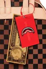 Mochila Sprayground mediana unisex, de cuero vegano con estampado a cuadros marrón y gris. Presenta un diseño de boca de tiburón con dientes blancos y encías rojas.