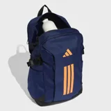 Mochila Adidas PrimeLift de color azul marino con detalles en naranja. Cuenta con compartimento principal con cierre, compartimento externo para notebook, bolsillos frontales y laterales, y correas de compresión laterales. El panel trasero es de malla para mayor ventilación.